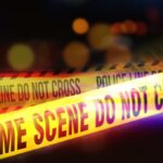 Yellow police tape marking a crime scene with blurred lights in the background