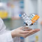A doctor holding a miniature shopping cart filled with various medication packs