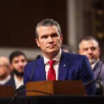 Individual in formal attire seated at a senate hearing
