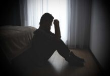 A silhouette of a woman sitting on the floor, appearing contemplative and distressed