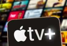 Close-up of a smartphone displaying the Apple TV+ logo with a blurred background of media thumbnails
