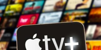 Close-up of a smartphone displaying the Apple TV+ logo with a blurred background of media thumbnails