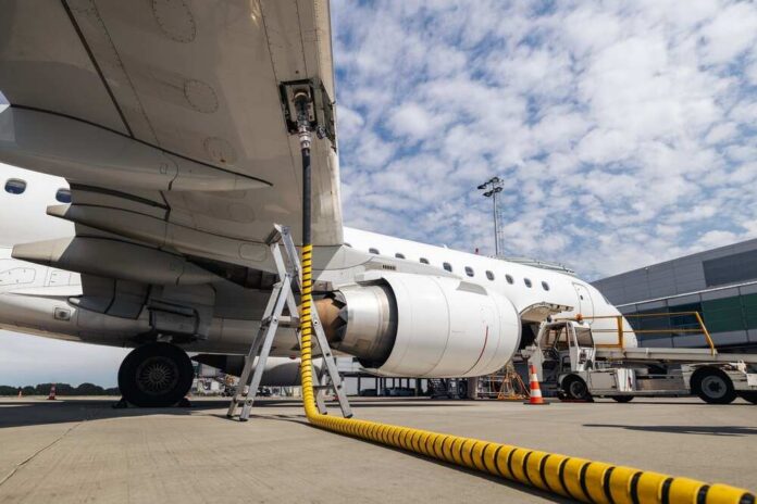 An airplane being fueled at an airport with visible ground support equipment