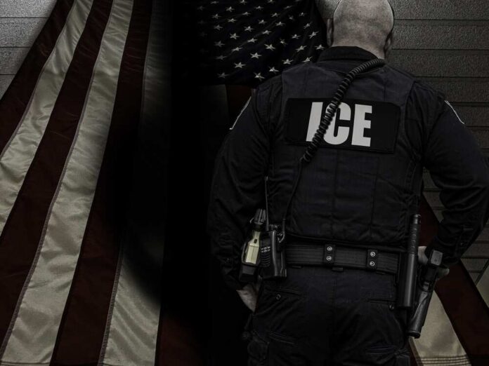 ICE agent standing in front of an American flag
