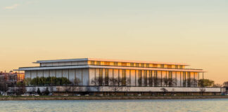 Modern building reflecting sunset over a river