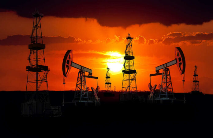 Silhouetted oil rigs against a vibrant sunset