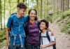 Controversial Family Truth: Kids Need Both Parents? A mother and her two children smiling while hiking on a forest trail