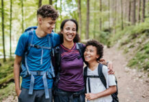 Controversial Family Truth: Kids Need Both Parents? A mother and her two children smiling while hiking on a forest trail
