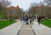 Students walking along a pathway on a university campus with historic buildings in the background