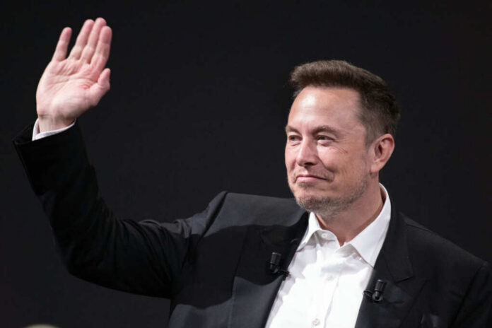 A man in a suit waving with a smile during a conference