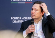 Individual speaking at a conference, holding a microphone
