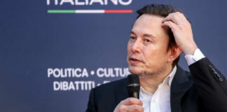 Individual speaking at a conference, holding a microphone