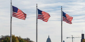Three American flags waving in front of the Capitol building in Washington D.C.