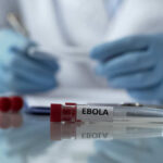 Ebola test tube on lab table with gloved researcher in background