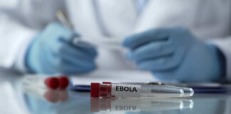 Ebola test tube on lab table with gloved researcher in background