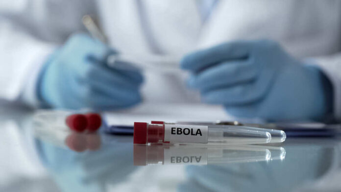 Ebola test tube on lab table with gloved researcher in background