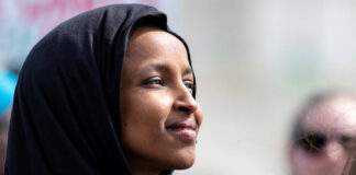 Woman wearing a black hijab looking thoughtfully into the distance