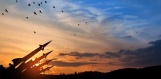 Silhouette of missiles against a colorful sunset with birds flying
