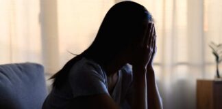 A silhouette of a person sitting with their head in their hands, conveying distress