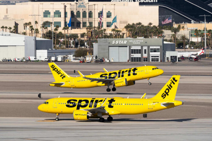 Two Spirit Airlines planes on a runway at an airport