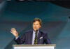 Totalitarian Future or Uprising? Carlson Speaks Out A man in a suit speaking at a podium with a microphone