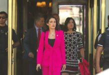 Woman in a bright pink suit walking out of a building