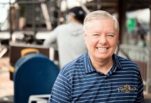 Graham’s Kharg Island Call: War or Just Talk? Smiling man in a striped shirt at an outdoor event