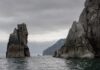 Rocky cliffs rising from the ocean under a cloudy sky