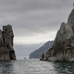 Rocky cliffs rising from the ocean under a cloudy sky