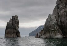 Rocky cliffs rising from the ocean under a cloudy sky