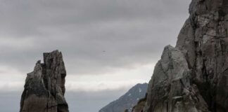 Rocky cliffs rising from the ocean under a cloudy sky