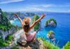 Escape Aging: Simple Travel’s Hidden Power Woman sitting on a cliff with arms raised, overlooking a beautiful ocean view