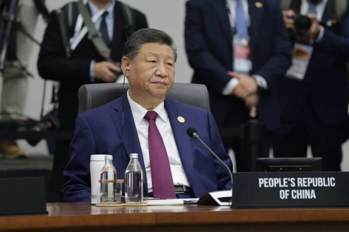 shutterstock_2699228133.jpg A seated leader at a conference table with a nameplate indicating the People's Republic of China