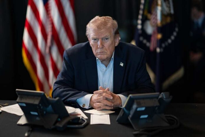 President,Donald,J.,Trump,Oversees,Operation,Epic,Fury,At,Mar-a-lago, A serious-looking man seated at a table with phones and an American flag in the background