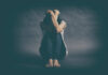 Period Symptoms: A Hidden Mental Health Threat? A person sitting on the floor with their arms wrapped around their knees, conveying a sense of distress