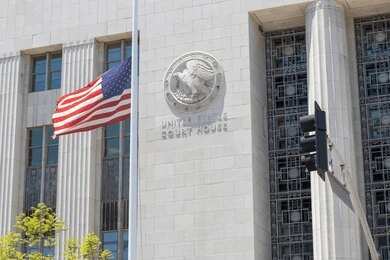 United States courthouse facade with American flag at half-mast