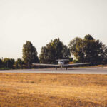 A small airplane on a runway surrounded by trees