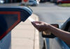 A hand inserting a letter into a blue mailbox