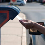 A hand inserting a letter into a blue mailbox