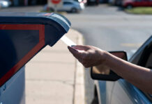 A hand inserting a letter into a blue mailbox