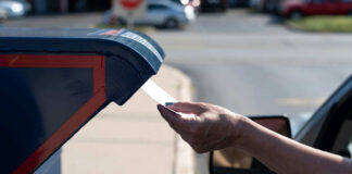 A hand inserting a letter into a blue mailbox