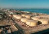 Aerial view of large oil storage tanks near a coastal area