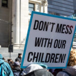 A protester holding a sign that reads 'DON'T MESS WITH OUR CHILDREN!'