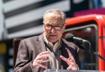 A man in a blazer speaking passionately at a podium with a microphone