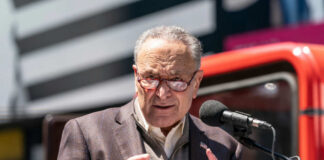 A man in a blazer speaking passionately at a podium with a microphone