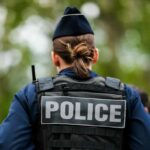 Back view of a police officer wearing a uniform and a police vest