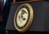 Prison Claim Unproven, Power Play Real Close-up of the Department of Justice seal on a podium
