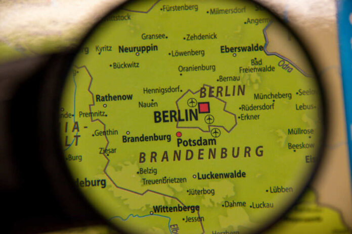 shutterstock_2412359367 Close-up view of a map showing Berlin and Brandenburg under a magnifying glass