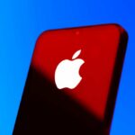 Close-up of a smartphone with the Apple logo against a red and blue background