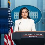 Woman in white suit speaking at White House press podium